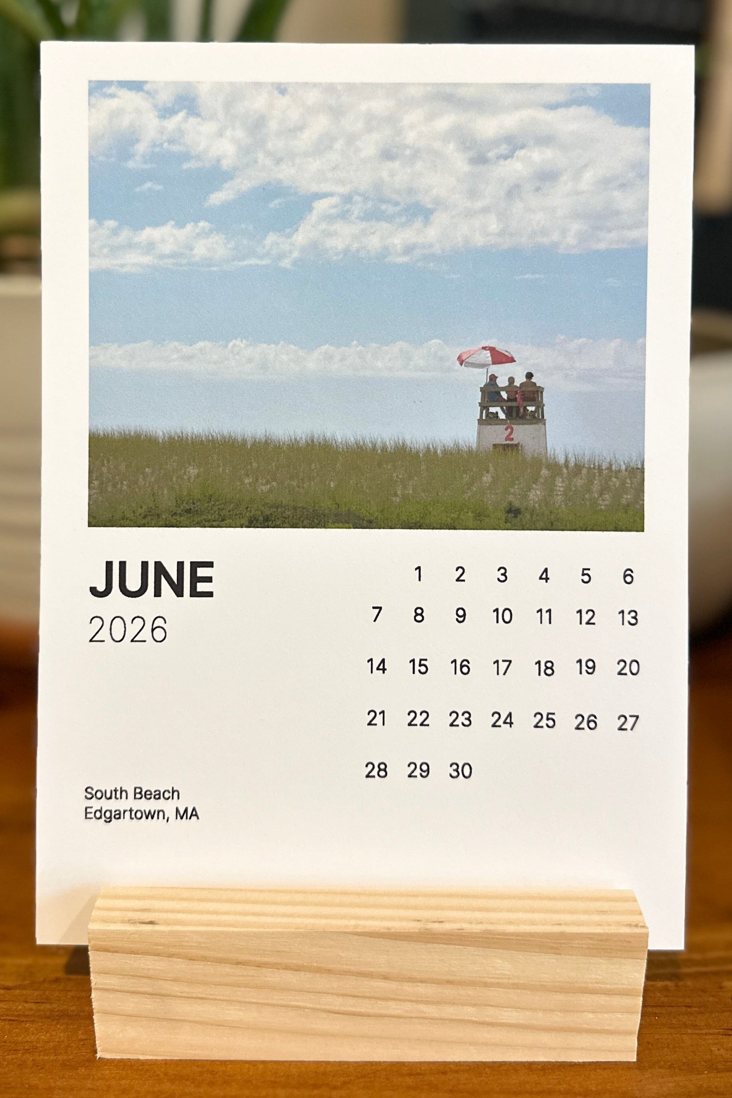 Calendar for June 2026 on a wooden stand with a scenic background
